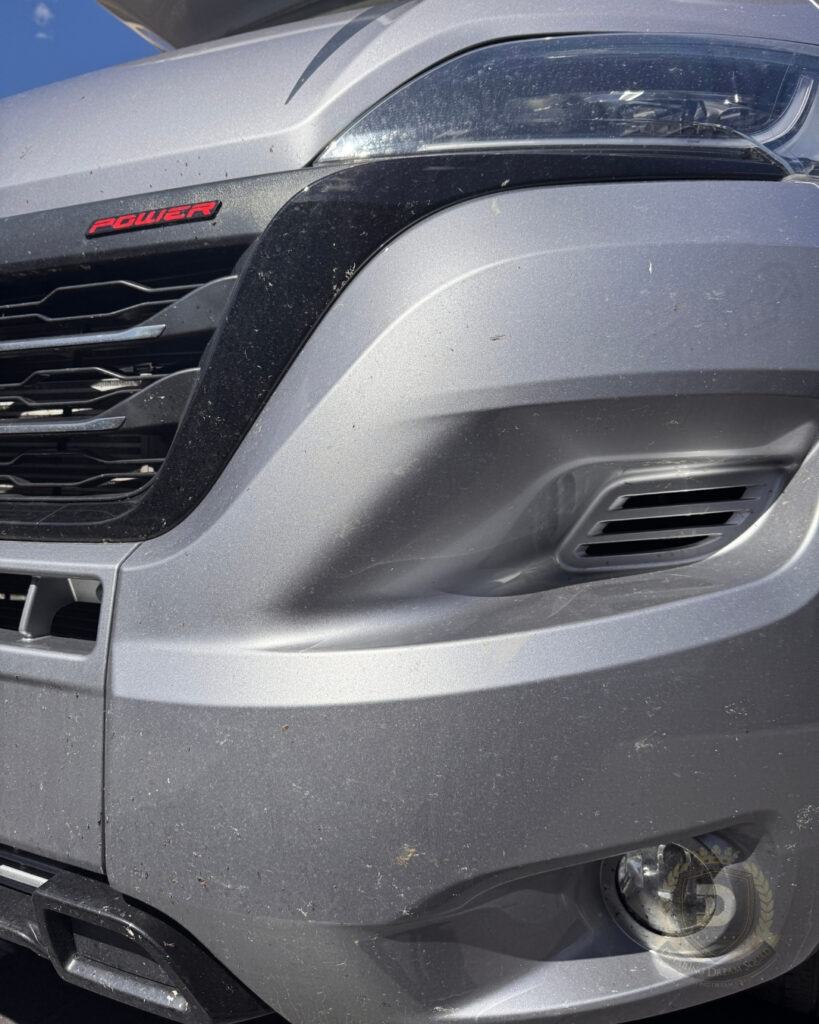 Close up of silver Jayco motorhome front bumper covered in bugs and road grime before professional detailing service in Sydney