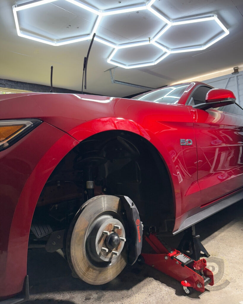Red Ford Mustang on jack with wheel removed for deep clean and ceramic wheel coating