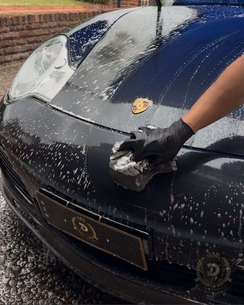 Detailing Dream Squad technician performing safe hand wash on black Porsche in Sydney as preparation for paint correction and ceramic coating service